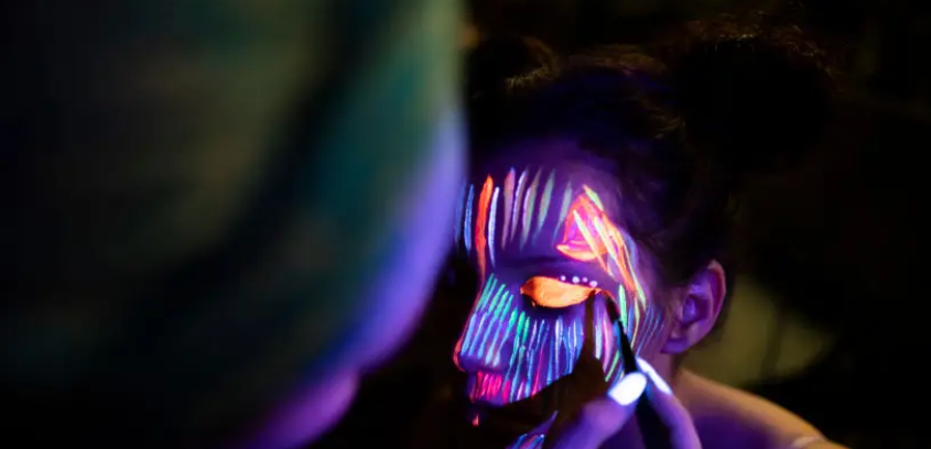 Participants maquillés avec peinture fluorescente sous lumière UV