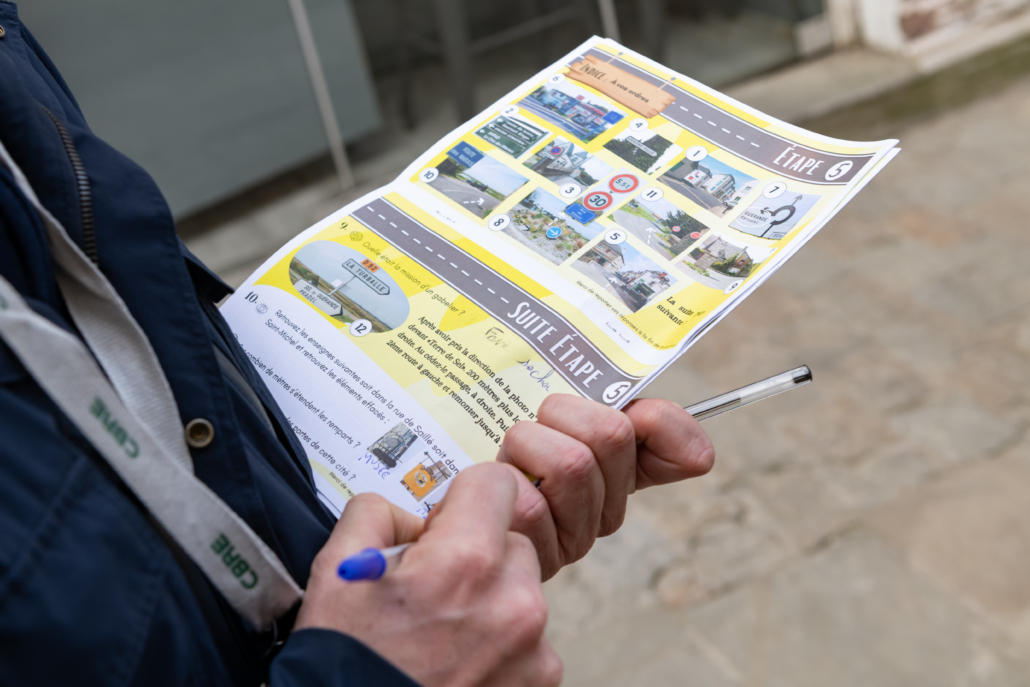 Participant complétant une feuille d'énigmes et d'orientation pendant un rallye en Citroën 2CV.