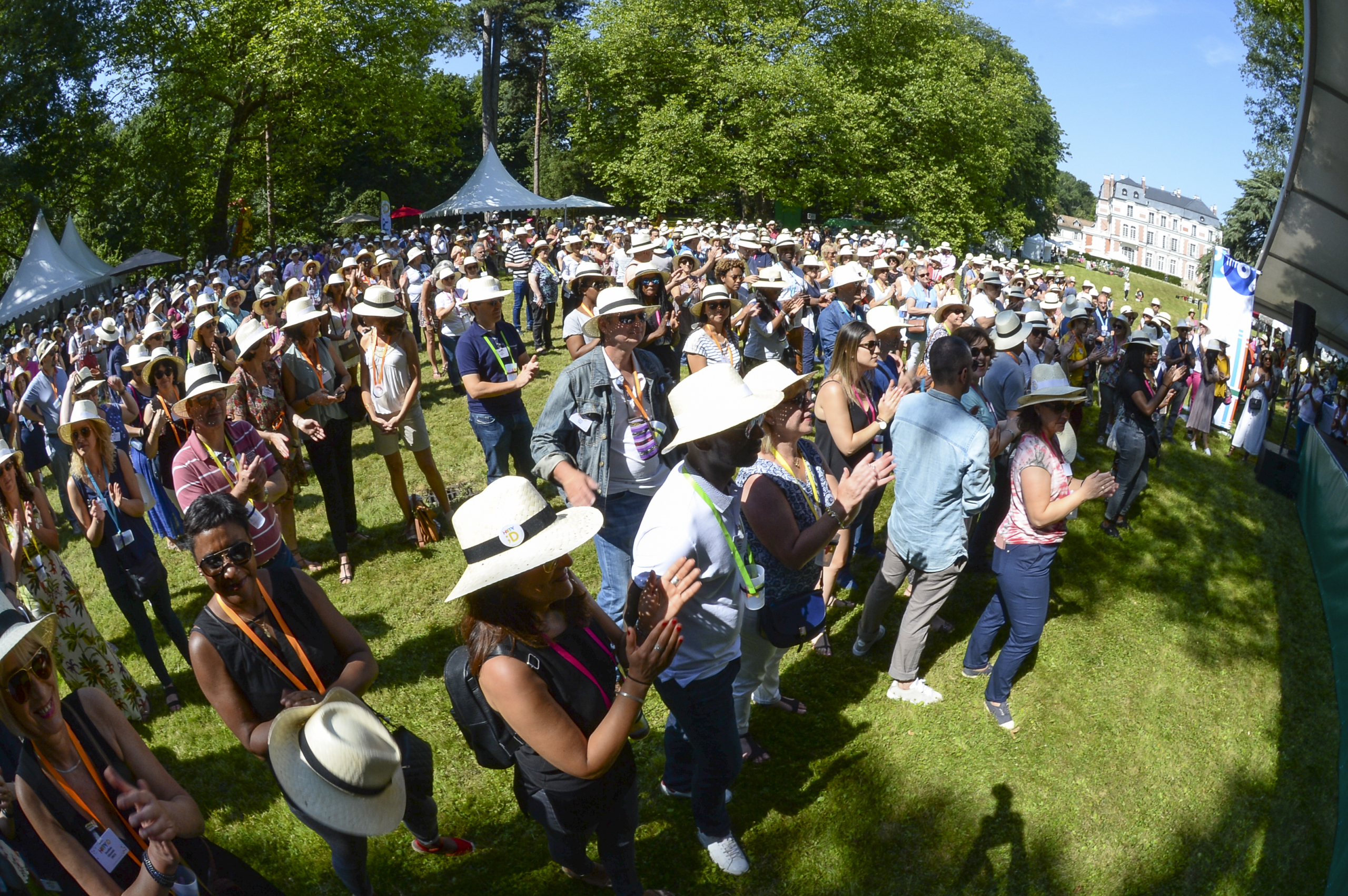 Participants réunis en extérieur devant une scène lors d'un rassemblement d'entreprise et d'une animation collective en plein air