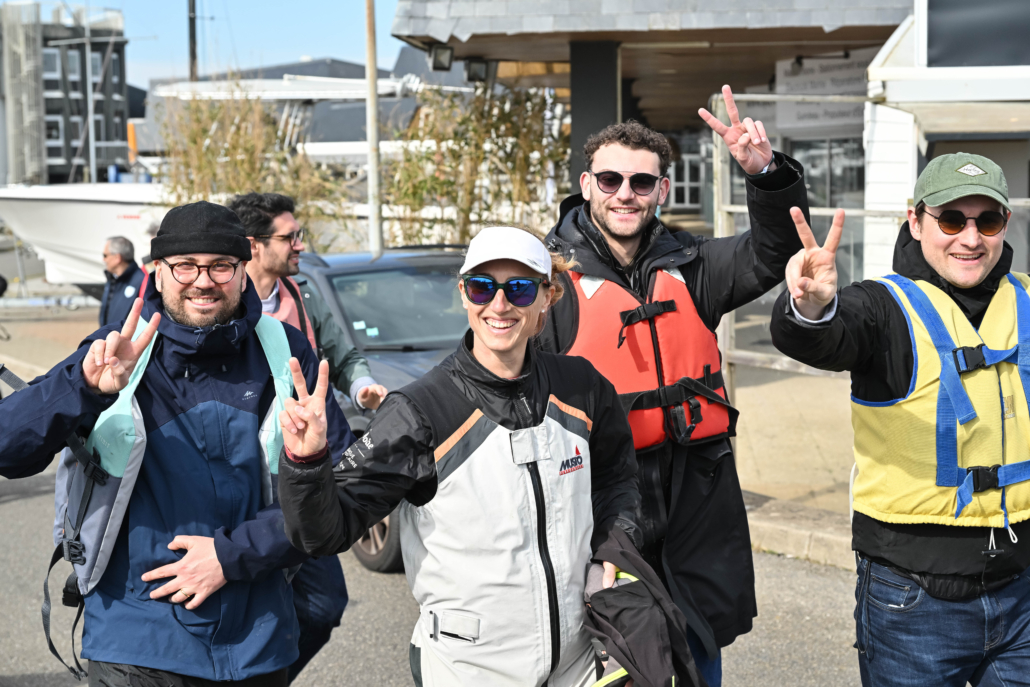 Participants équipés de gilets de sécurité rejoignant les pontons avant une régate en voilier lors d’un séminaire d’entreprise.