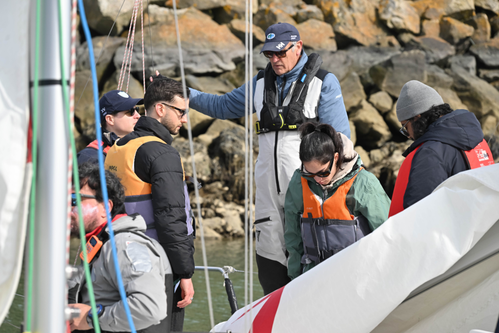 Skipper expliquant les consignes de navigation à un équipage lors d’une activité de cohésion en mer.
