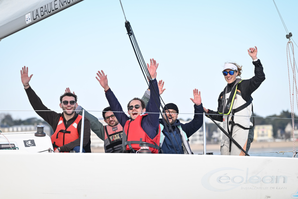 Équipage participant à une régate d’entreprise à bord d’un voilier sur la baie.