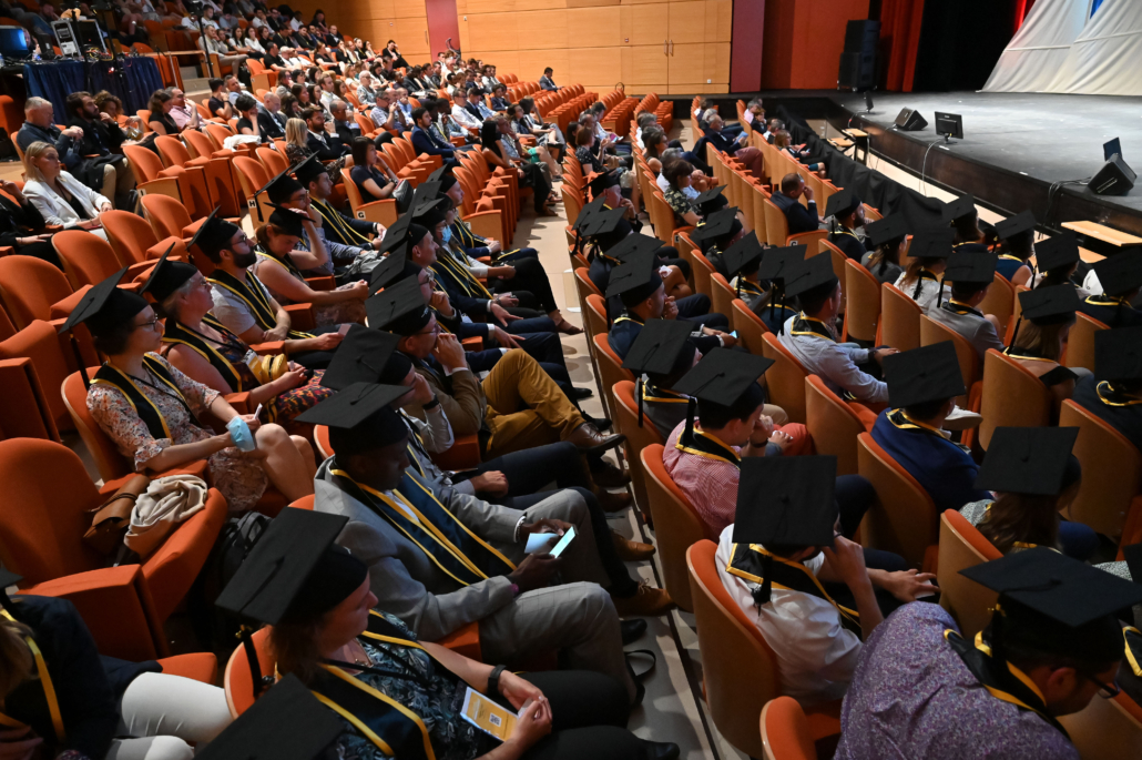 Public et diplômés assistant à une cérémonie officielle dans un auditorium équipé pour une conférence