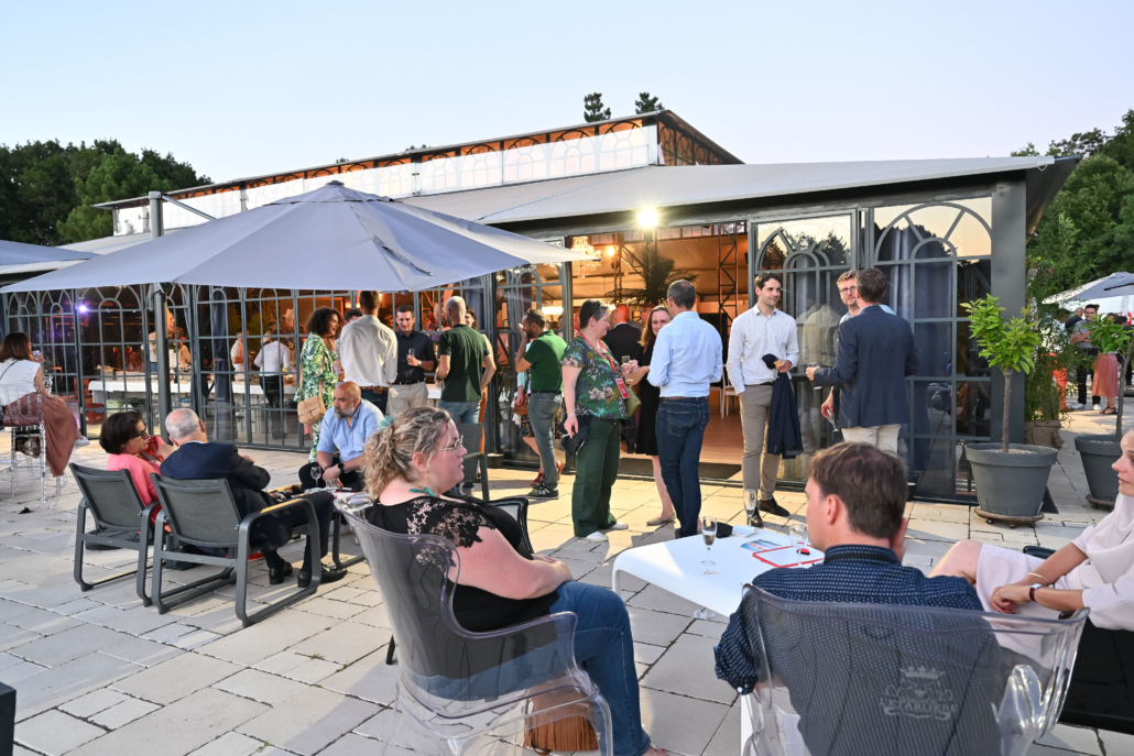 Participants échangeant lors d'un cocktail en terrasse pendant une soirée d'entreprise dans un lieu de réception