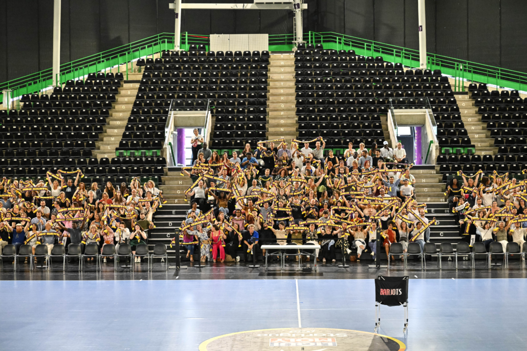 Participants réunis dans les tribunes d’une arena sportive lors d’une soirée d’entreprise privatisée.