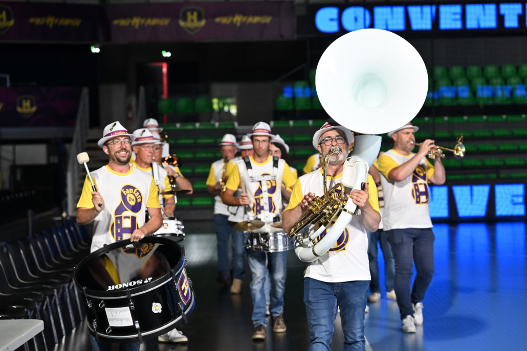 Fanfare déambulant dans une arena lors d’une soirée festive d’entreprise.