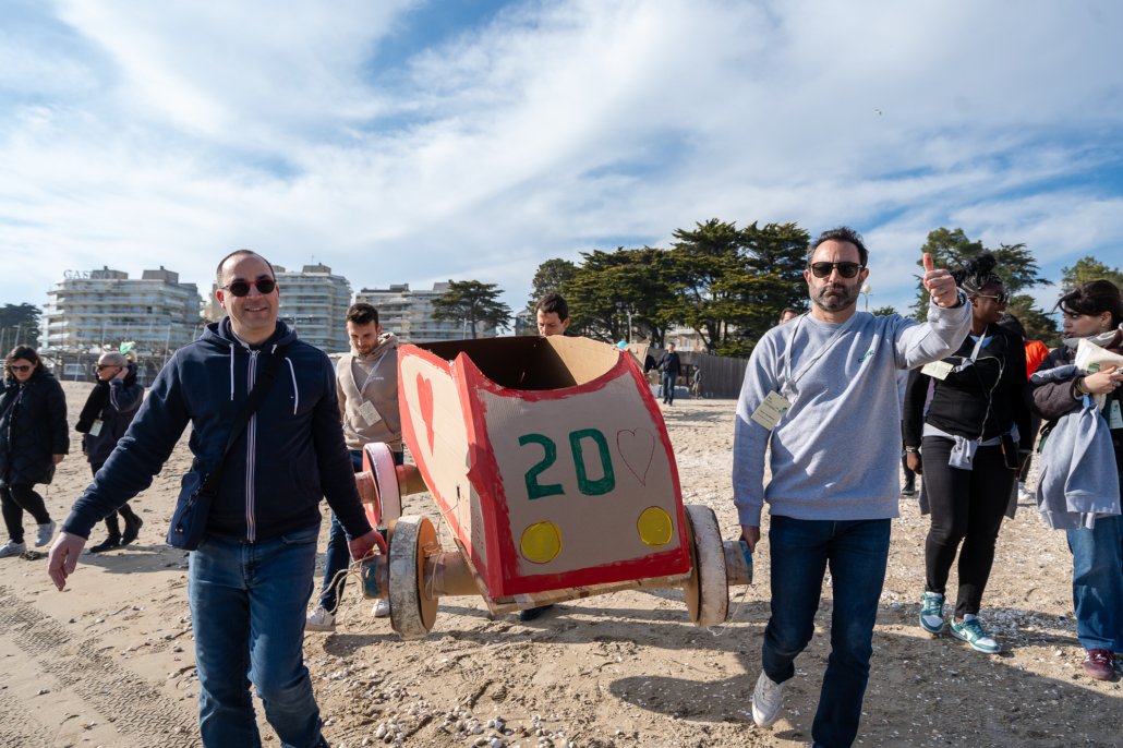 Collaborateurs transportant une caisse à savon en carton conçue lors d'une activité de cohésion d'équipe en bord de mer.