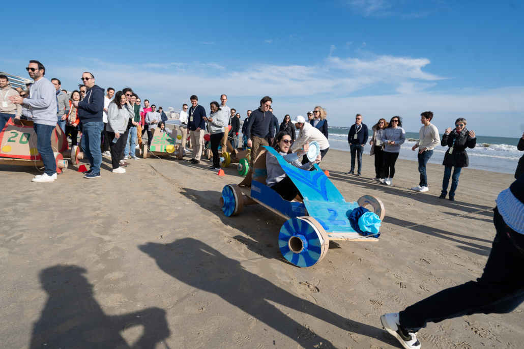 Participant installé dans une caisse à savon pendant une course organisée sur la plage devant ses collègues.